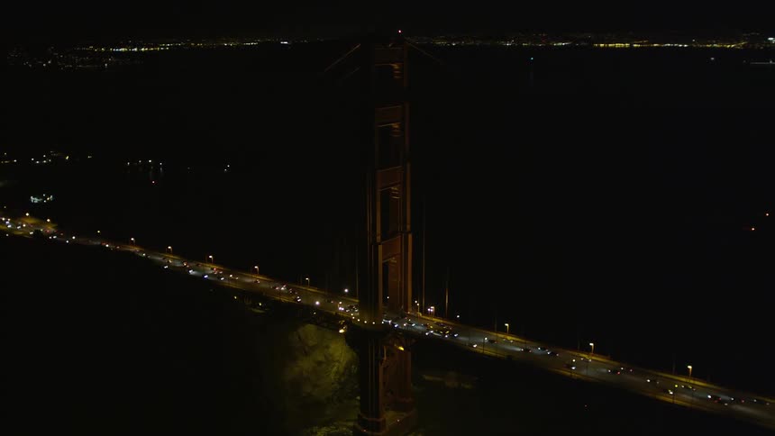 Aerial panorama of a long bridge over the sea of a metropolis with vehicle traffic at night