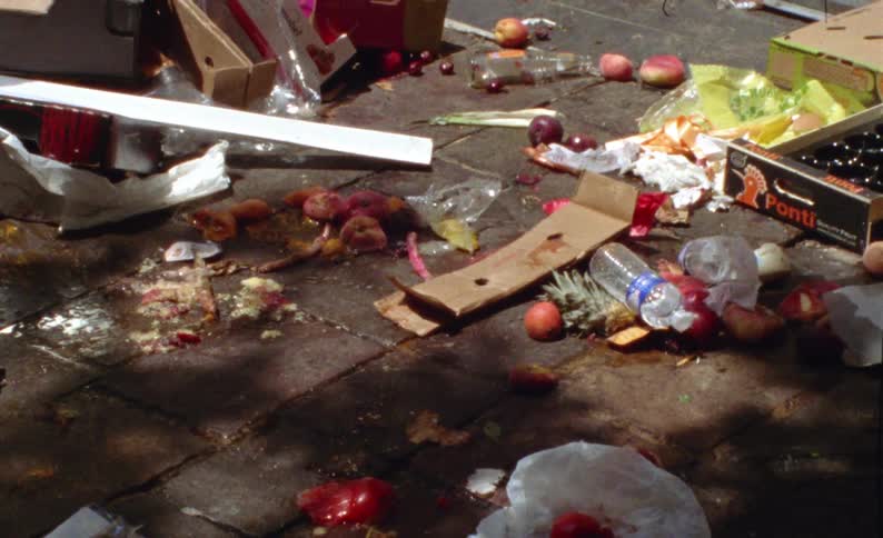 Outdoor street with fruits and vegetables and boxes thrown like trash on the ground