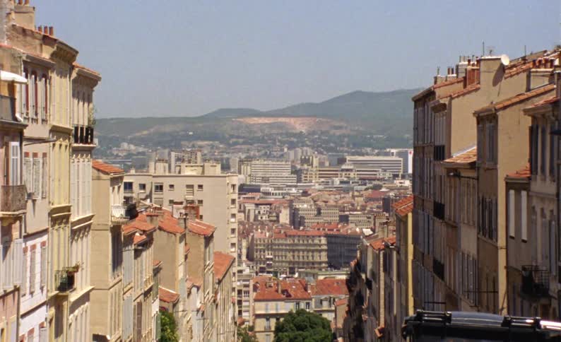 A street with several buildings and houses on the sides and all have the same shades of beige