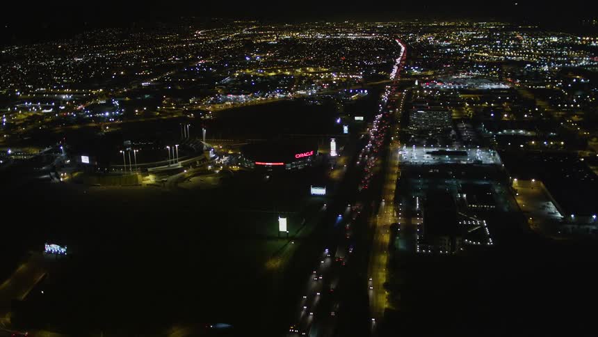 Aerial panorama of a metropolis at night with highways and vehicle traffic