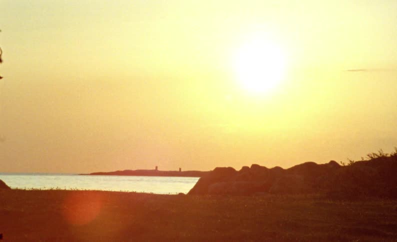 The sun shining very brightly in the sky in a region close to the sea