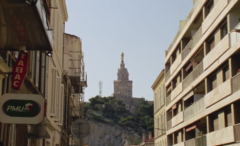 Street of a city with urban buildings and in the background a church on a hill