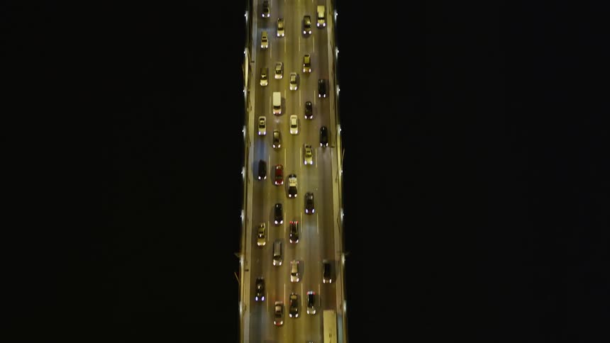 A freeway with several cars passing on an asphalt street at night