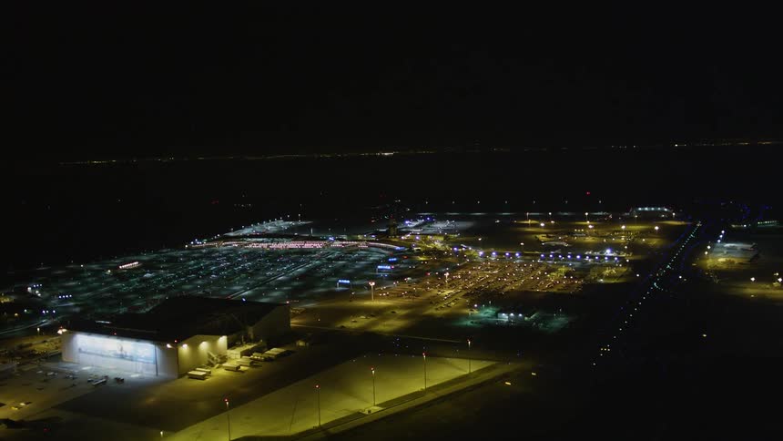 Nighttime aerial view of a welllit industrial area with multiple buildings and parking lots