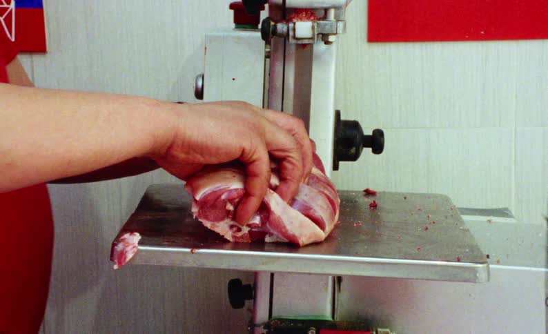 Hands of a butcher cutting a piece of meat into steaks