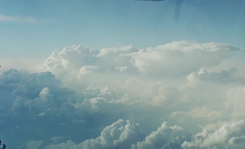 View from the window of a vehicle moving through the sky with clouds