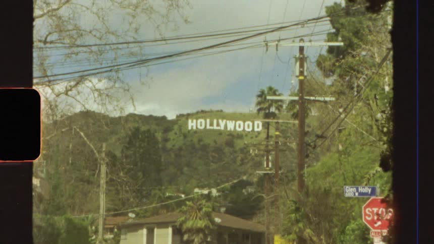 Street with vehicle traffic and view of the hollywood sign on a mountain