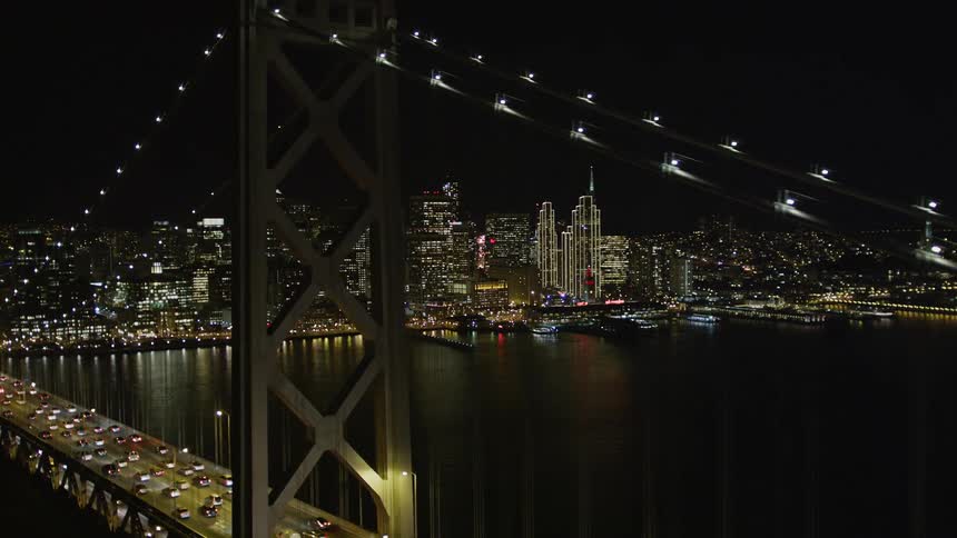 Traffic moves across a double deck bridge near a large urban area