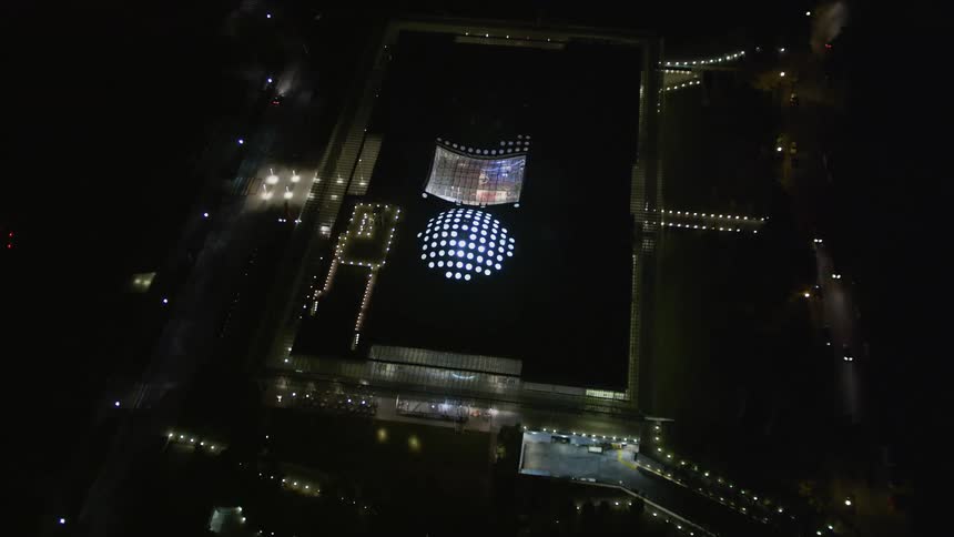 A long building with a lit up dome and skylight in a city
