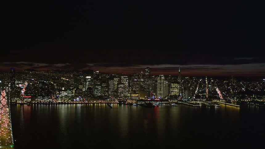 Aerial panorama of a long bridge over the sea overlooking a metropolis illuminated at night