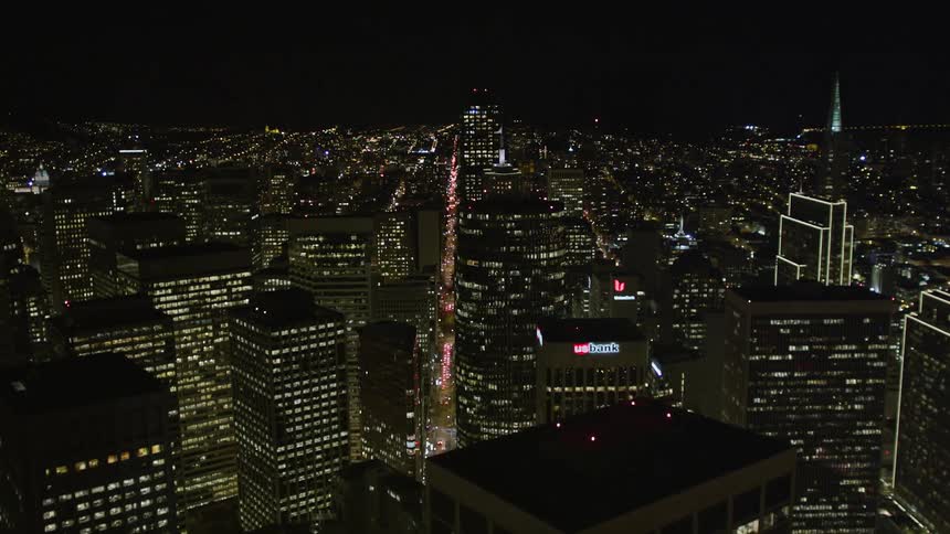 A city center with huge buildings at night and the city lights are on