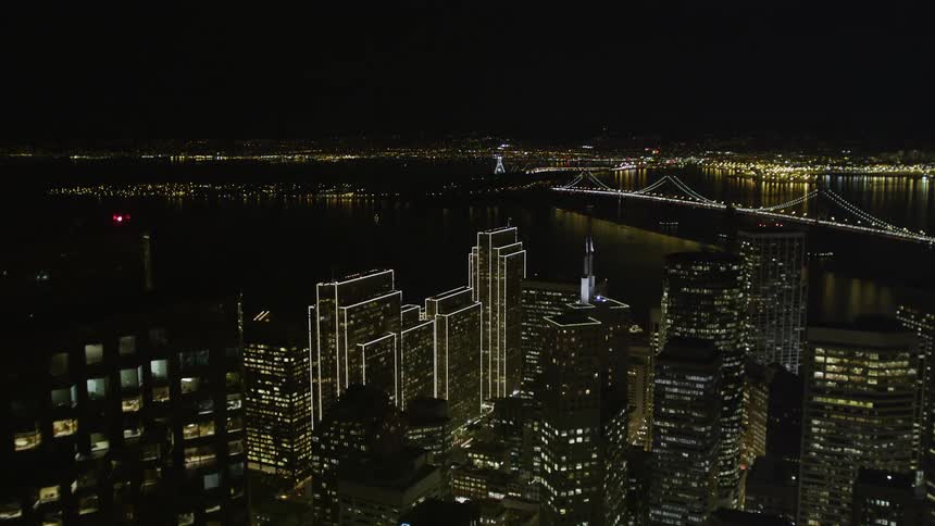Aerial view of a metropolis with a skyscraper illuminated at night and the seaside