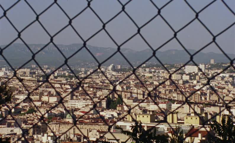 A view from a window with a grille where there is to see a city with many houses