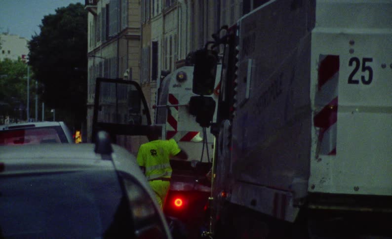 A worker in a fluorescent yellow jacket is putting something into a utility truck
