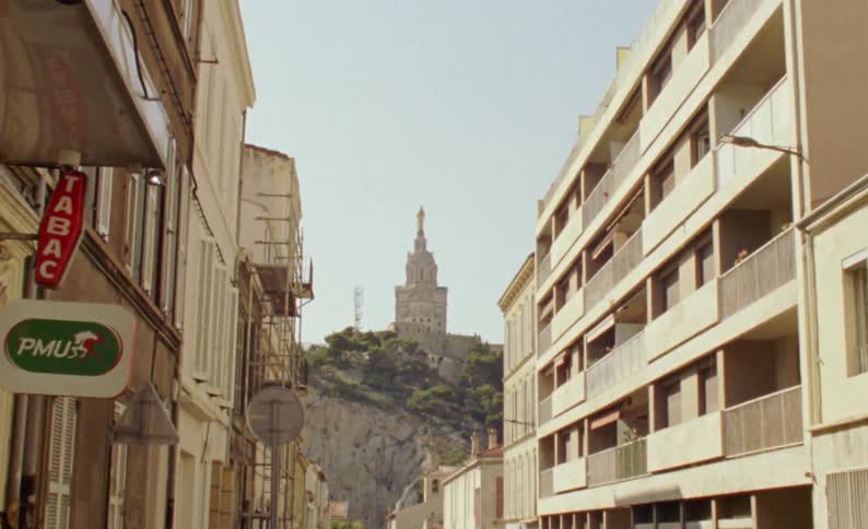 Point of view of a city street with old and urban buildings and in the background on a hill a tower with ancient architecture