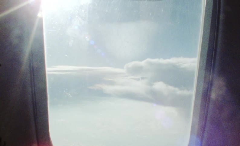 Clouds float by outside an airplane window