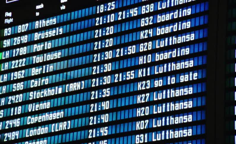 A closeup of a flight information display system showing departure times and destinations