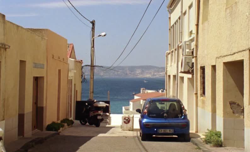 Alley of a residential neighborhood in the suburbs with a parked car overlooking the sea and coast