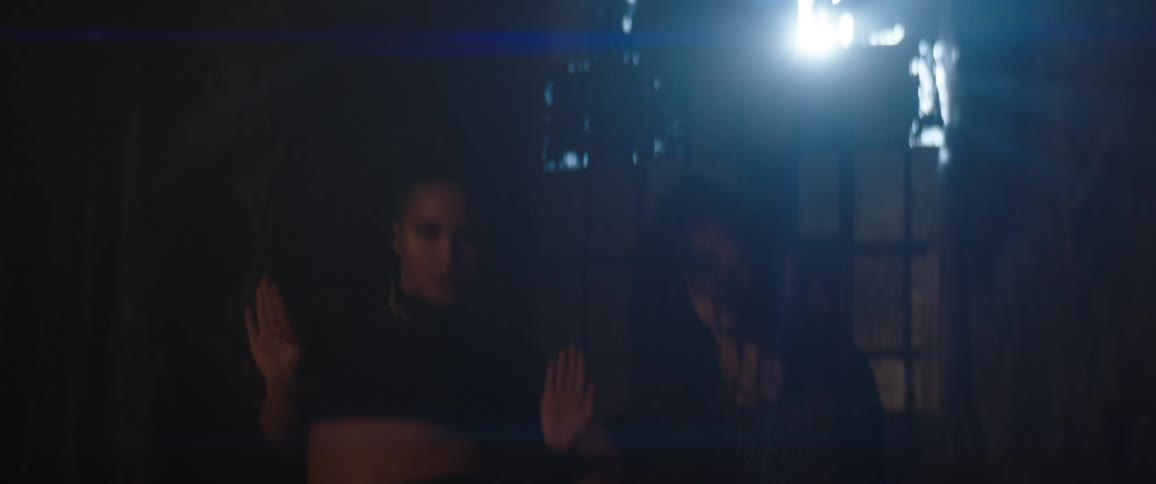 Two young women and dancers dancing a choreography inside a studio with low lighting