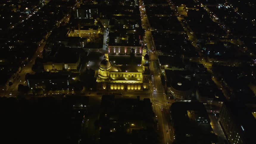Aerial panorama of a metropolis illuminated at night with intersections with vehicle traffic and a cathedral in the center