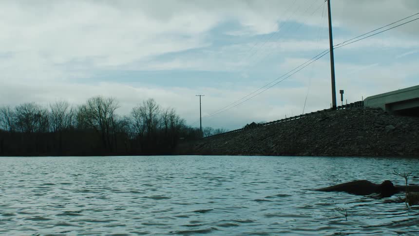 Power lines parallel bridge crossing water on a cloudy day