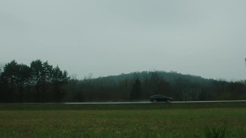 Natural scenery of a highway with a car passing at high speed on a wet road