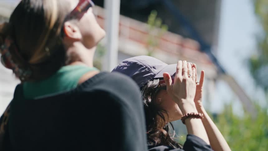 Two women stare into the sky while wearing sunglasses