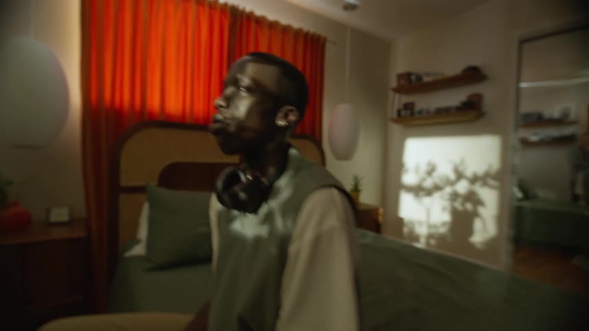 Side portrait of a young man sitting on the bed in his room and the reflection of sunlight on his face