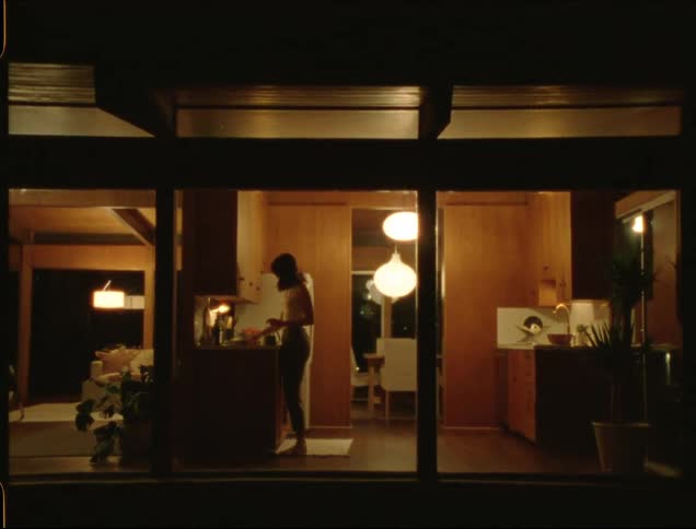 A woman walks across her home to the kitchen