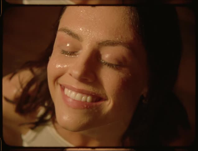 A woman smiles while being rained on