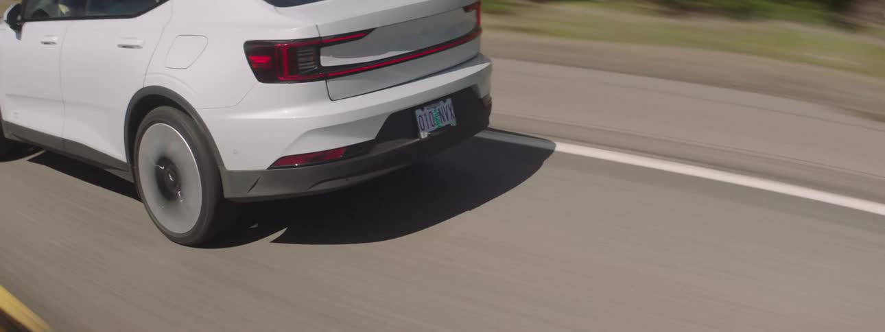Vehicle drives along highway passing narrow fields at base of mountains
