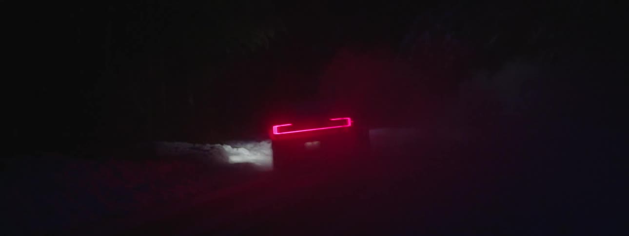 Vehicle with a neon led on the back driving on a snowy road at night
