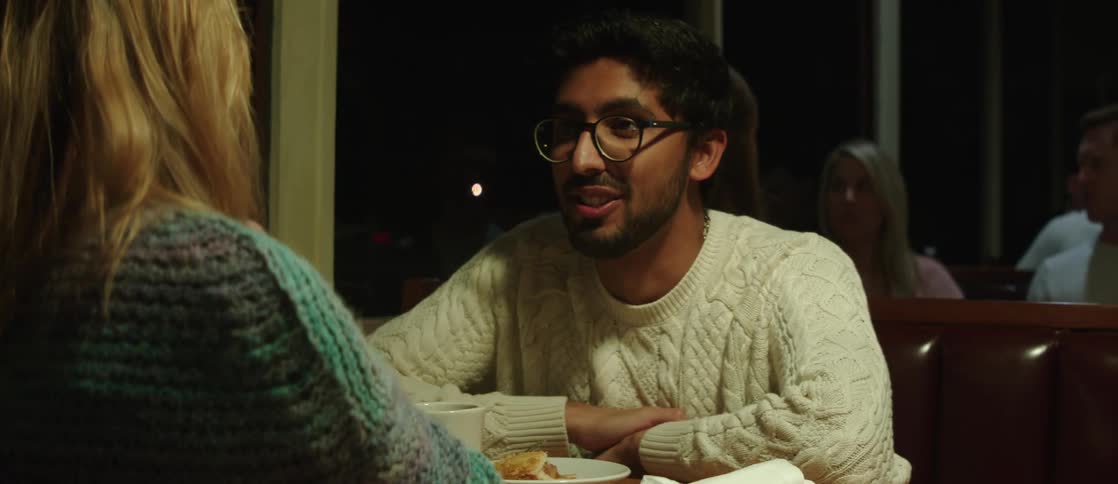 Couple sitting in restaurant booth at night smile while talking