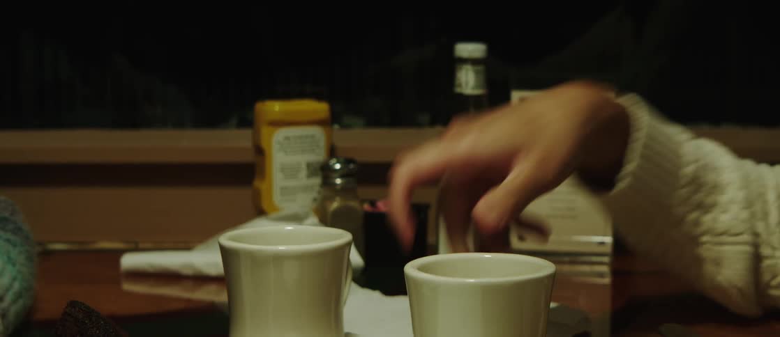 A person places a coffee cup over a table in a restaurant