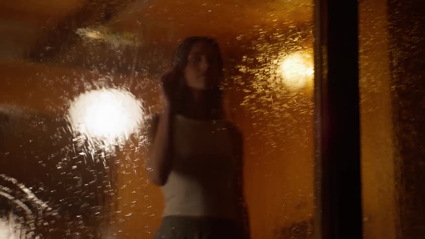 A clip of a lady in a room standing beside the window