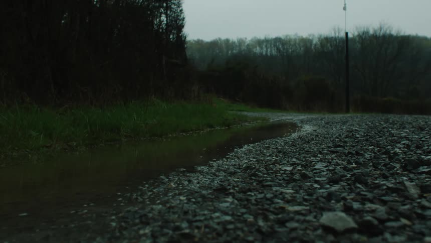 A puddle of water next to a stone floor and raindrops are falling in the puddle of water