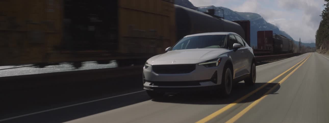 White suv car traveling along a paved road next to a freight train during the day