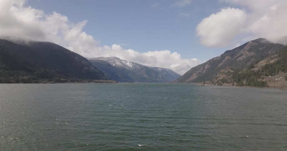 Waves flow across water between mountains on a cloudy day