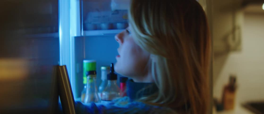 A woman takes wine glasses out of the fridge