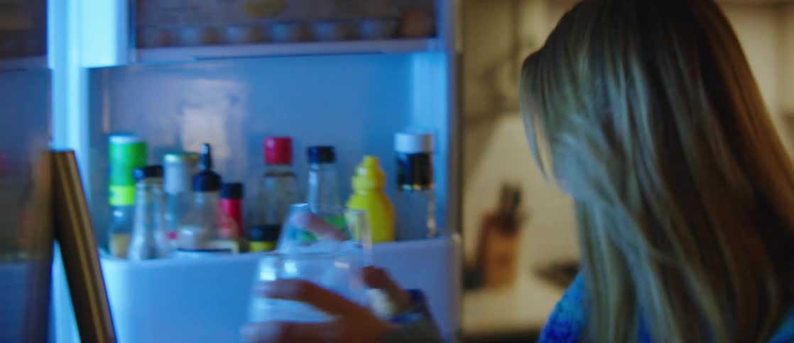 A clip of a lady taking a beverage drink from the fridge