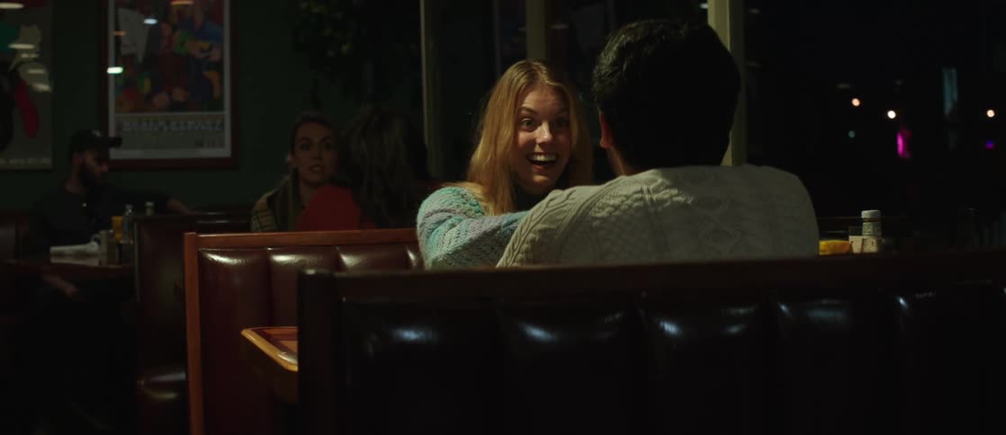 Woman and man sitting opposite each other at a restaurant table while talking and smiling