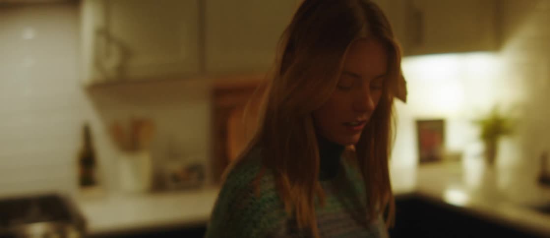 Portrait of a young woman closing the refrigerator door and walking around the kitchen