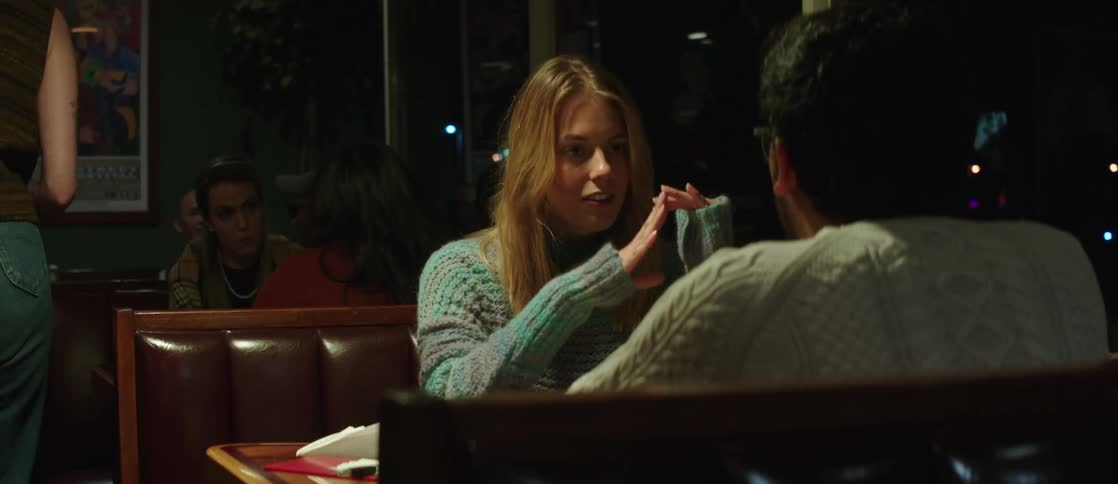 Couple sitting at a table in a restaurant at night talking happily