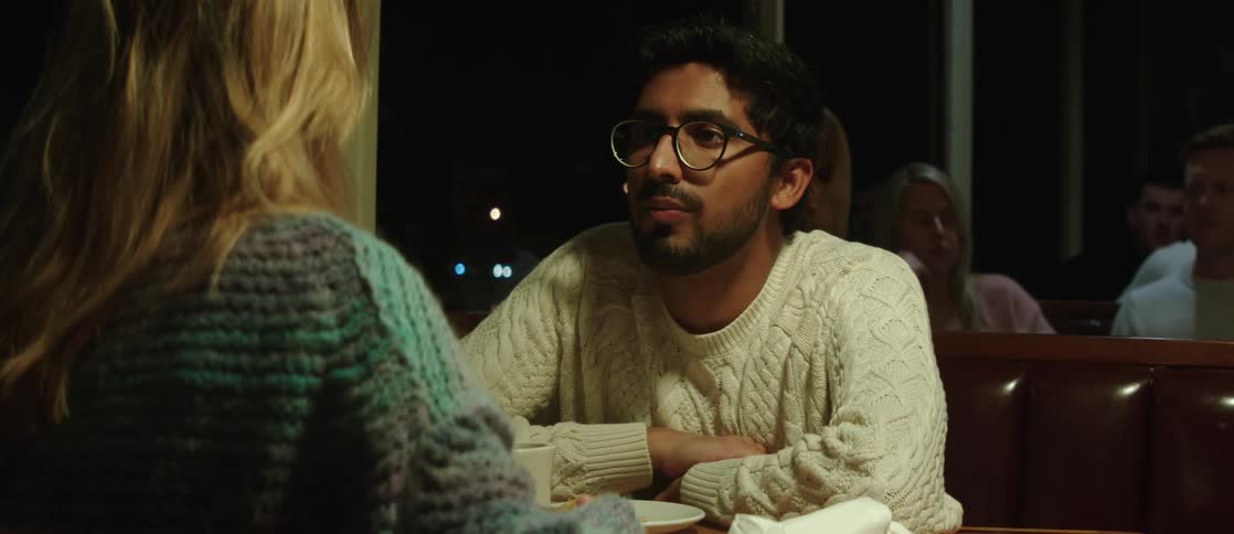 During a date a couple sits in a booth near the window of a restaurant at night