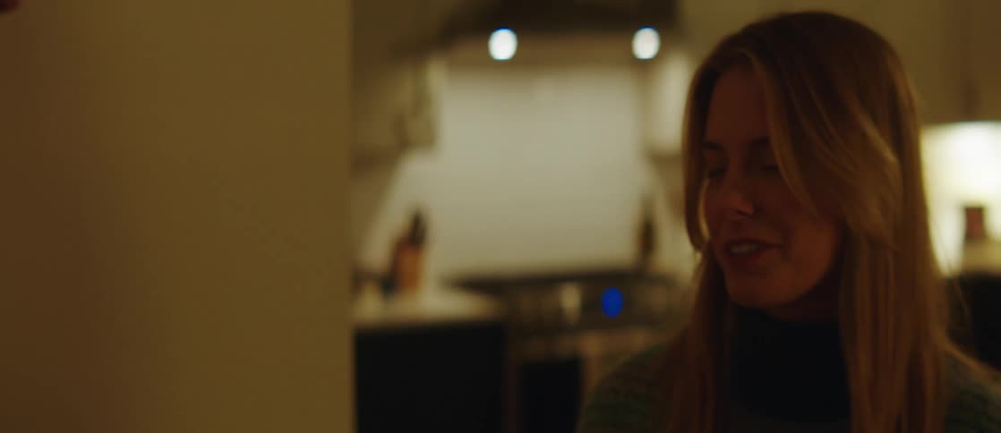 Portrait of a smiling young woman in the kitchen talking to a man