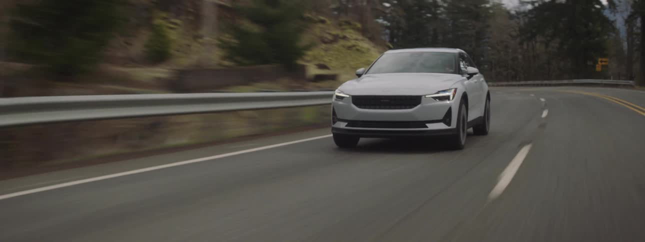 Modern white sports car traveling along a paved road in a natural environment