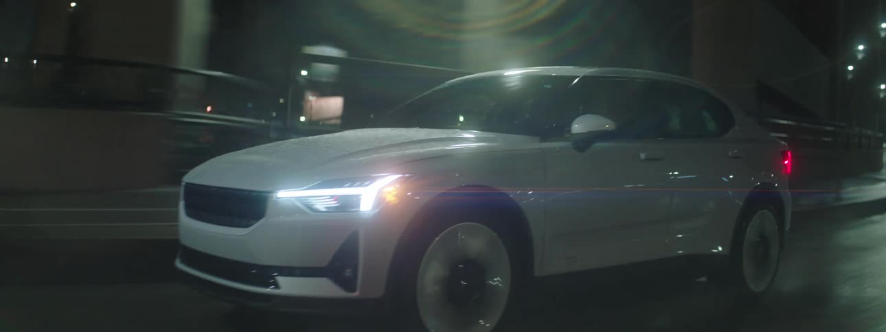 Car drives along highway passing through city at night