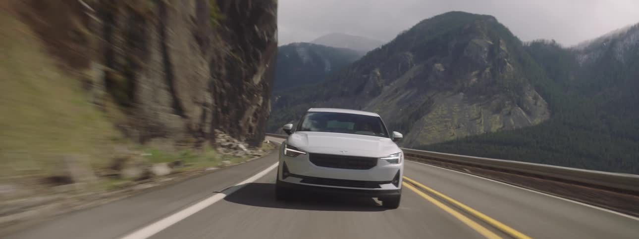 The car is driving on the road on the cliff of a mountain