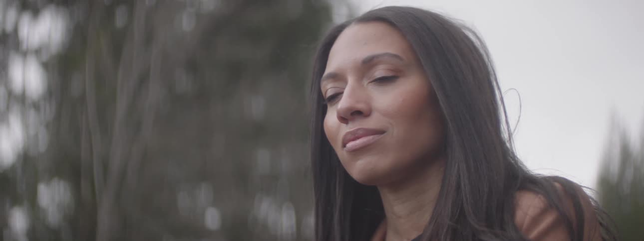 A woman gazes into the distance then closes her eyes appearing relieved