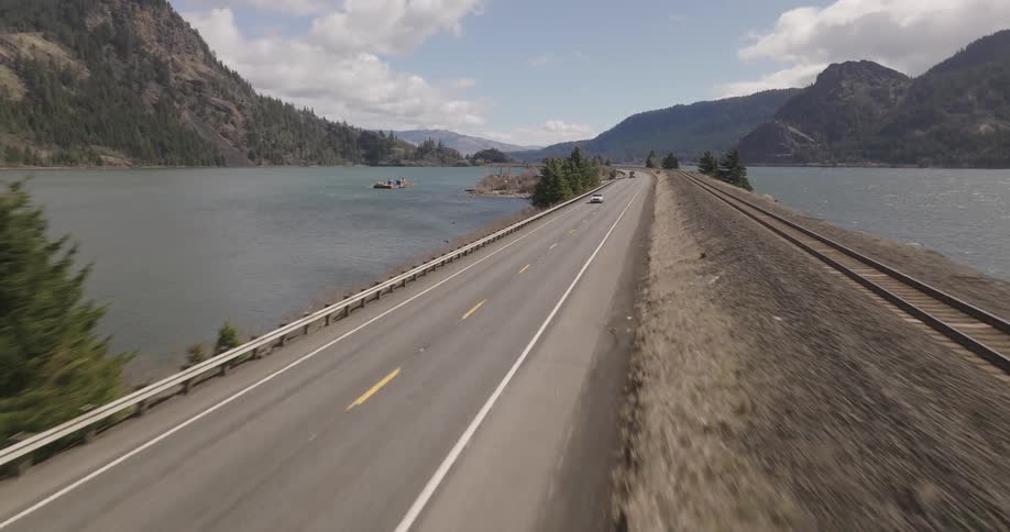 Cars drive past the train tracks on the water